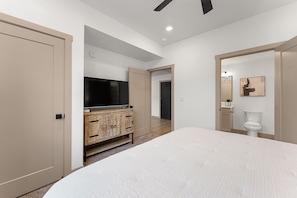 Ein Schlafzimmer mit einem Bett, einem Fernseher, einem Holzschrank und einer Toilette.
