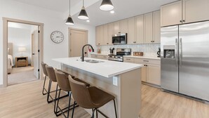 A modern kitchen with a central island, stainless steel appliances, and pendant lighting. - Copper House 2 Bedroom Condo (Hurricane)