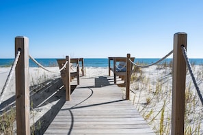 A wooden boardwalk leading to beach chairs with a rope barrier, overlooking the ocean. - Laughin Place 7 Bedroom Home by Peace Vacations (Pawleys Island)