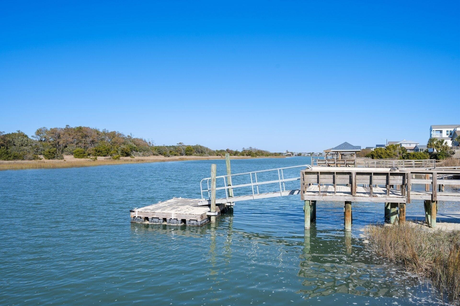 A wooden pier extending into calm water, with a small boat docked at the end.