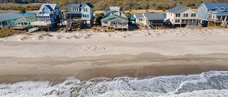 Beachfront houses with ocean views, wooden decks, and a sandy beach.