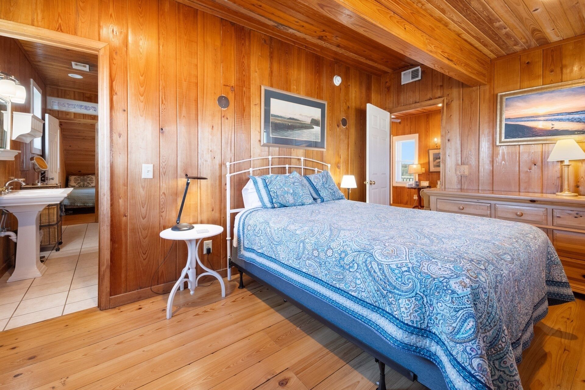 A wooden cabin bedroom with a bed, bedside table, and a dresser.
