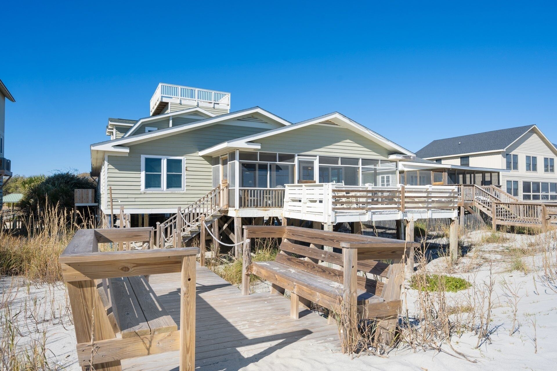 Een strandhuis met meerdere woningen verbonden door een houten terras.