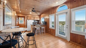 Ein Holzinterieur mit Küche, Essbereich und großen Fenstern.