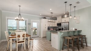 Une cuisine moderne avec des meubles blancs, un îlot central et des luminaires suspendus.