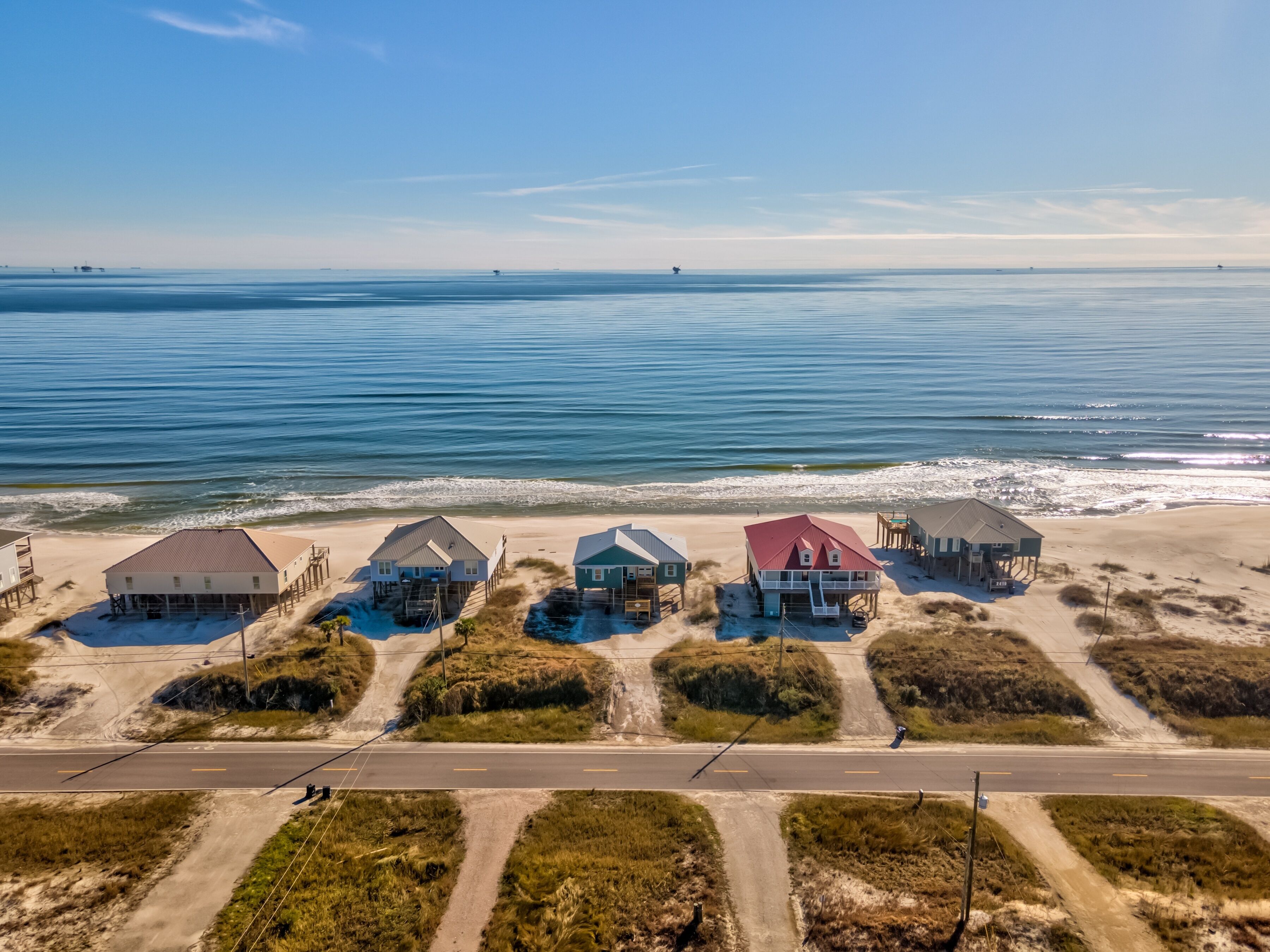 A coastal property with multiple beachfront houses, a road, and a beach.