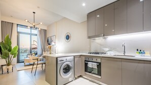 A modern kitchen with a built-in washer, oven, and a dining area with a view. - Contemporary 2BR in Azizi Park Avenue, Nad Al Sheba by Deluxe Holiday Homes (Dubai)