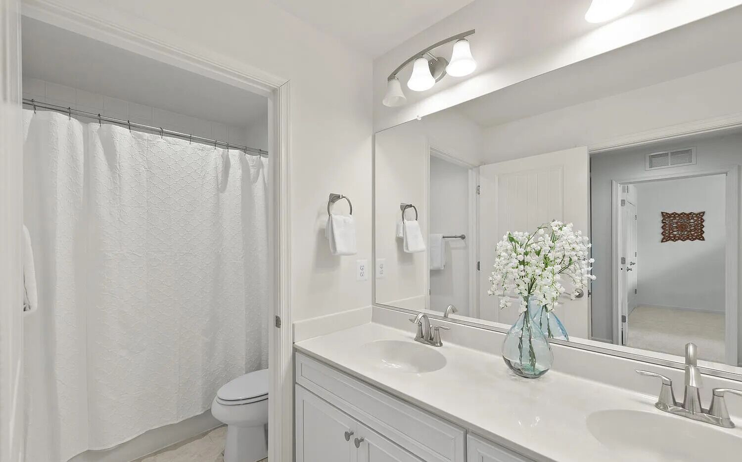 A modern bathroom with a white sink, vanity, and shower curtain.