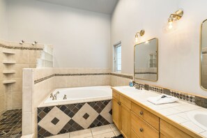 A bathroom with a bathtub, two sinks, a vanity with drawers, a shower area, and a window. - Hawk Haven_Hot Tub, Hydronic Heat, Game Room w/ Pool Table, Foosball, Arcades, 2790sqft (Truckee)