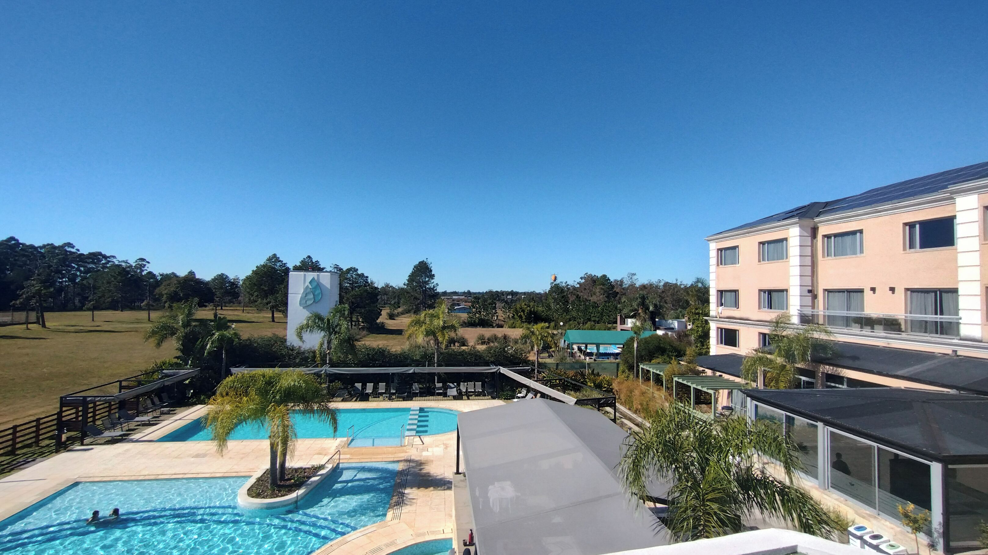 A hotel with a swimming pool, outdoor seating area, and a view of the surrounding landscape.