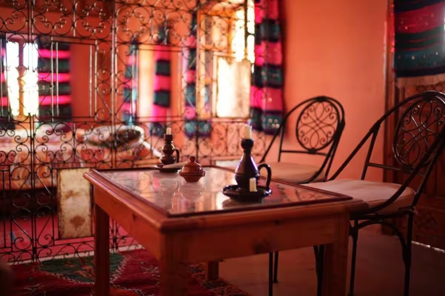 A room with a wooden table, two chairs, and a decorative iron gate.