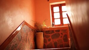 Una escalera con un muro de piedra y una ventana con vidrios blancos.