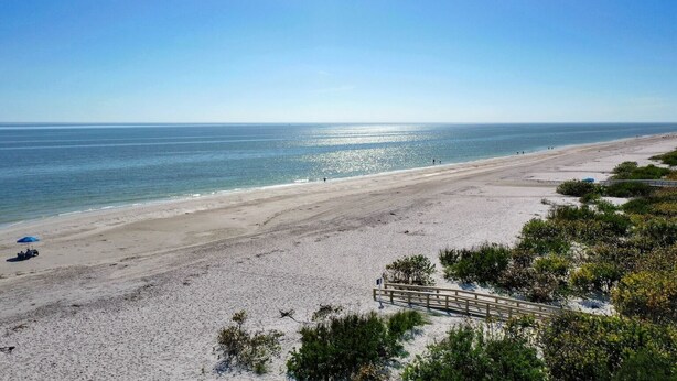 Ein Strand mit einer Holzpromenade und freiem Blick auf den Ozean.