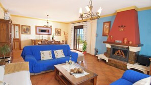 A living room with a blue sofa, a wooden coffee table, and a fireplace. - Fabulous villa, airco, pool, WIFI. Walking distance to village. Amazing views. (Comares)