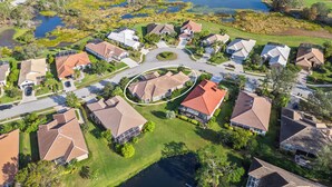 An aerial view of a residential area with houses, a central roundabout, and a lake. - Lakewood Ranch–Spacious 3BR Home with Den by RVA (Bradenton)