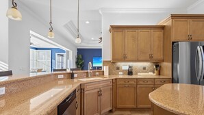 A kitchen with granite countertops, wooden cabinets, stainless steel appliances, and pendant lighting. - Lakewood Ranch–Spacious 3BR Home with Den by RVA (Bradenton)