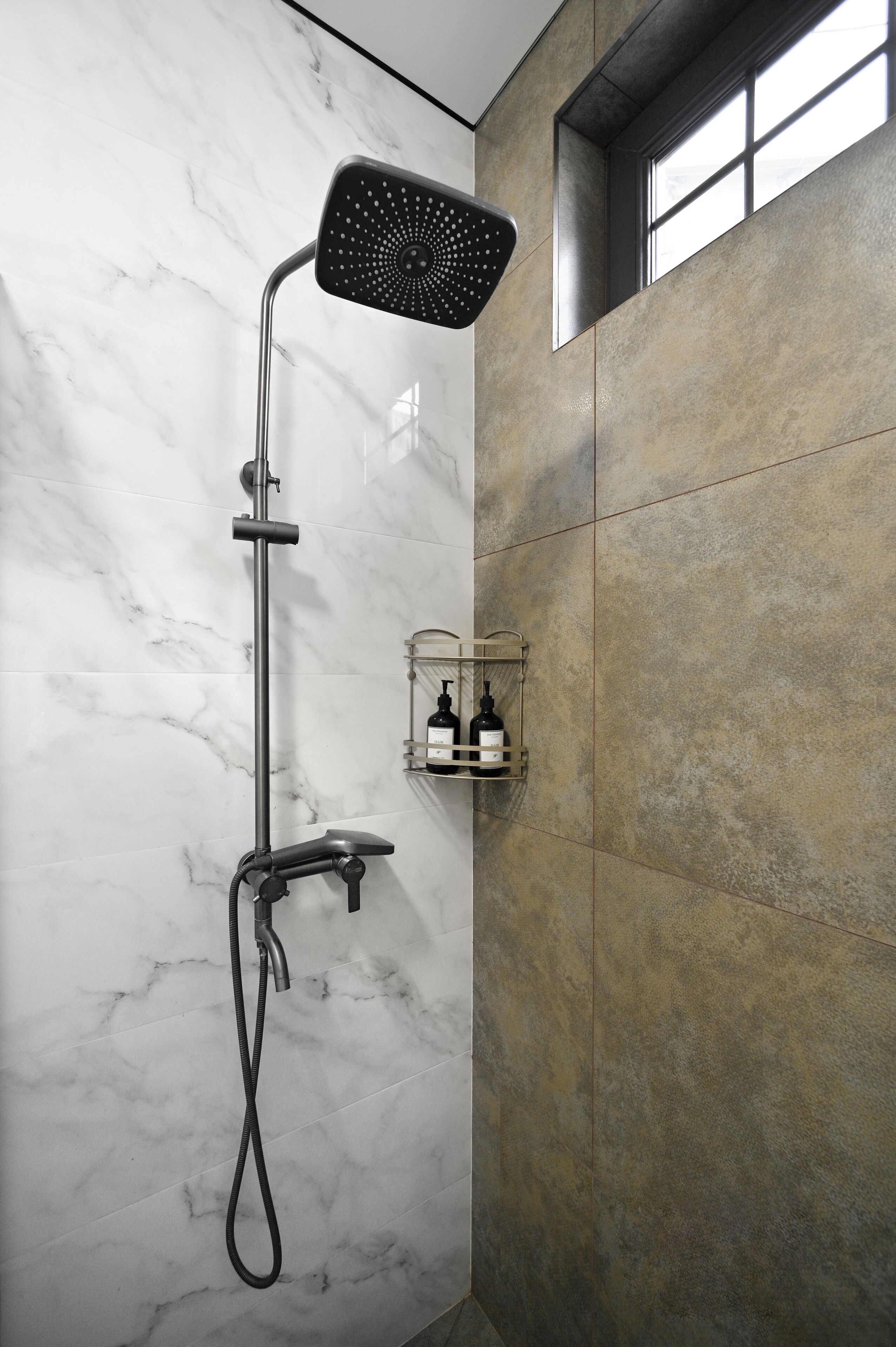 Une douche moderne équipée d’un pommeau de douche à main, d’un flexible de douche et d’un robinet mural.
