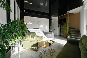 A modern hotel lobby with a reception desk, green sofas, and potted plants. - Mon Invite Hotel (Yerevan)