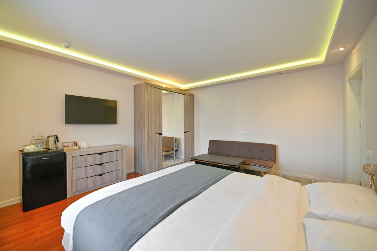 A modern hotel room with a bed, a dresser, a mirror, and a flat-screen TV.