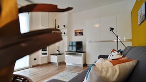 A modern living room with a grey sofa, a flat-screen TV, and a standing lamp. - Studio With Gym Near Milan Metro (Milan)