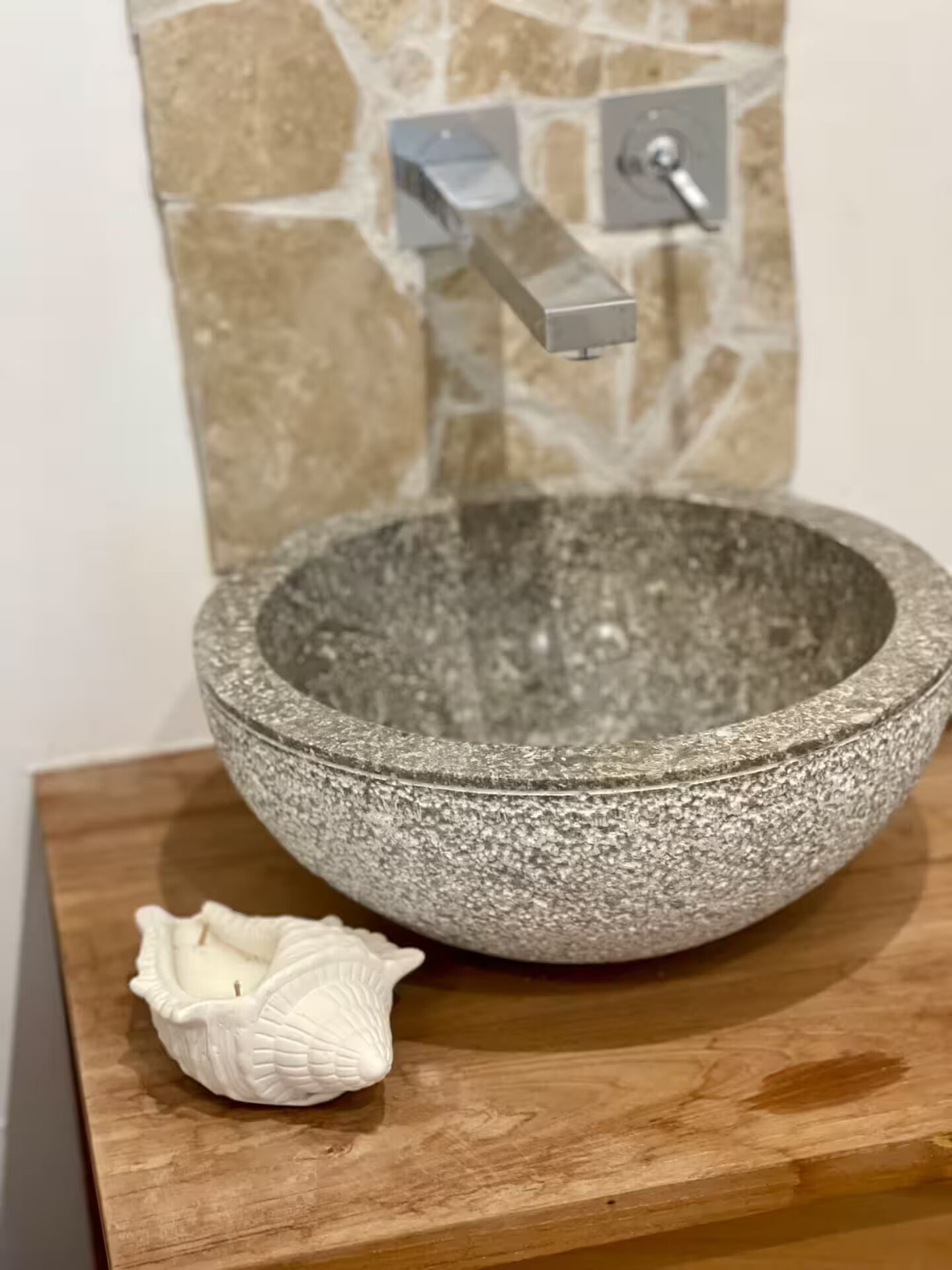 A stone sink with a faucet on a wooden countertop.