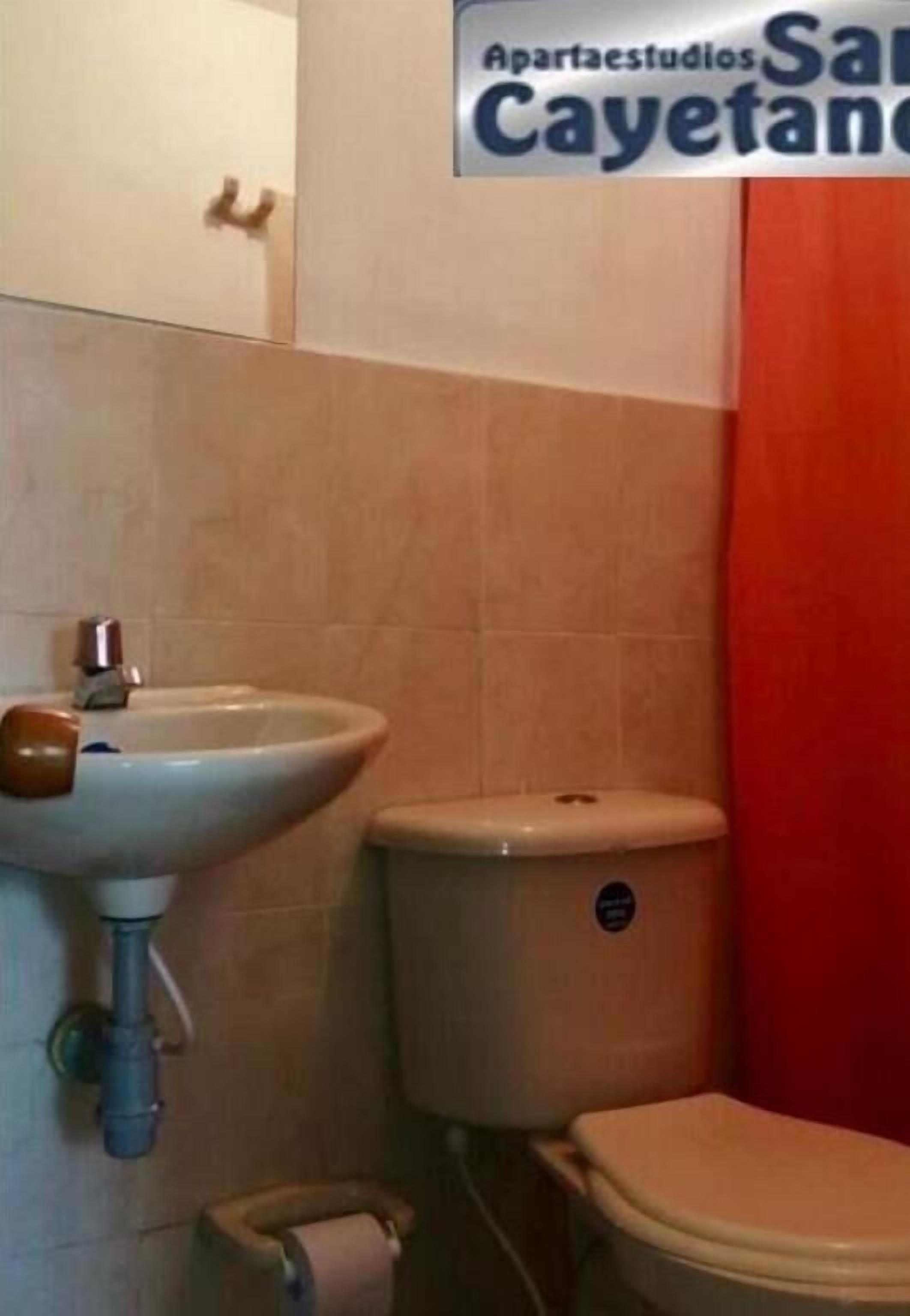 A bathroom with a sink, toilet, and a red curtain.