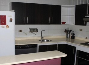 A kitchen with black cabinets, a white countertop, a sink, and a dishwasher. - Apartaestudios San Cayetano (Cali)