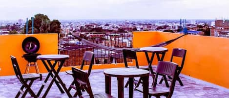 Une terrasse sur le toit avec des sièges en plein air, une vue sur la ville et une enseigne indiquant « Apartamentos San Cayetano ».