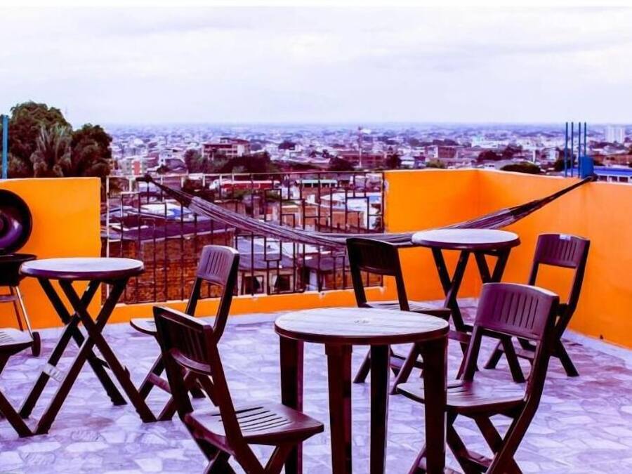 A rooftop terrace with outdoor seating, a view of the city, and a sign for 'Apartamentos San Cayetano'.