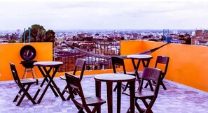 Eine Dachterrasse mit Sitzgelegenheiten im Freien und Blick auf die Stadt, mit einem Schild für 'Apartamentos San Cayetano'.