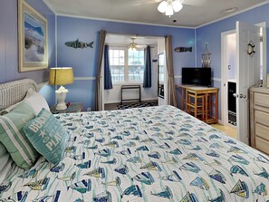 Een slaapkamer met een bed, een televisie, een bureau en een dressoir.