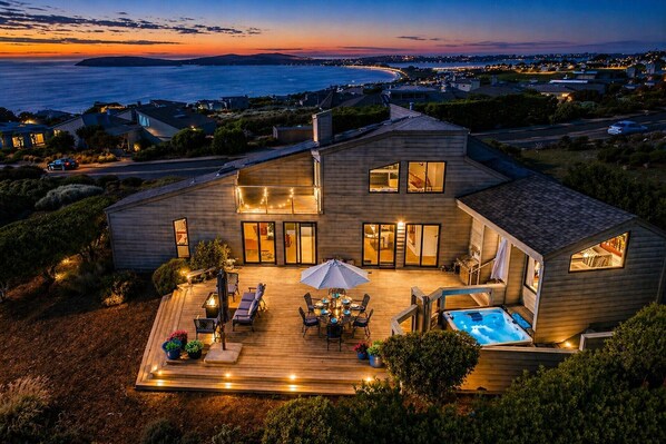 A modern house with a deck, outdoor seating, and a hot tub.