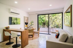Un salon moderne avec un coin repas, de grandes fenêtres et une vue sur la verdure.