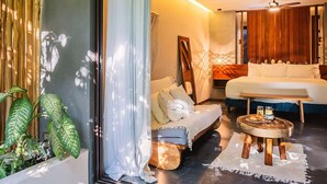 Une chambre d’hôtel moderne, dotée d’un canapé, d’un lit, d’une table ronde en bois et d’une grande fenêtre avec des rideaux.