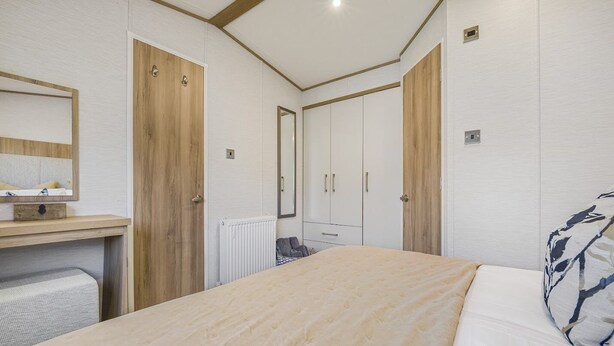 A bedroom with a bed, a dresser, a mirror, and a radiator.