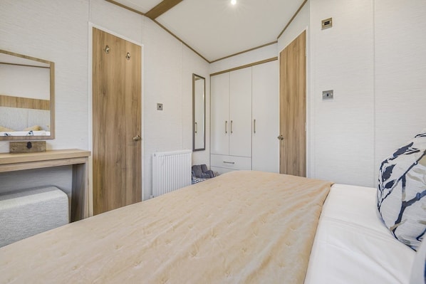 A bedroom with a bed, a dresser, a mirror, and a radiator.