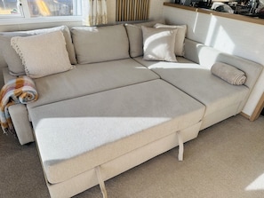 A large, light-colored sectional sofa with multiple cushions and a throw blanket. - Seaviews Porthkerry Holiday Park Sleeps 6 (Barry)