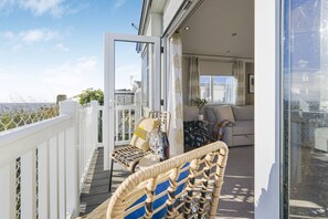 A balcony with wicker furniture, a sofa, and a glass door leading to an interior space.