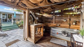 Una cabaña rústica con interior de madera, un lavabo de metal y un recipiente metálico grande.