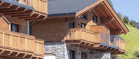 A multi-story wooden building with balconies, stone walls, and a sloped roof.