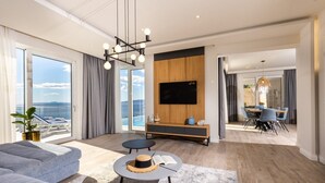 A modern living room with a large TV, a dining area, and a view of the sea. - Luxury Villa with pool and panoramic sea view! (Potomje)