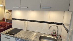 Een compacte keuken met witte kastjes, een granieten aanrechtblad en een roestvrijstalen spoelbak.
