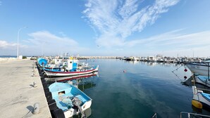 Un port où des bateaux sont amarrés, une jetée et une mer calme sous un ciel dégagé.