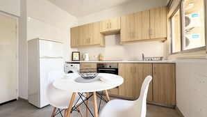 Une cuisine moderne avec des meubles en bois, un four encastré et une table à manger blanche avec des chaises.
