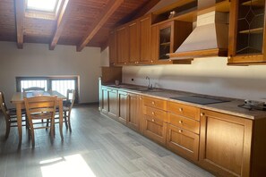 A kitchen with wooden cabinets, a large window, and a dining area with chairs.