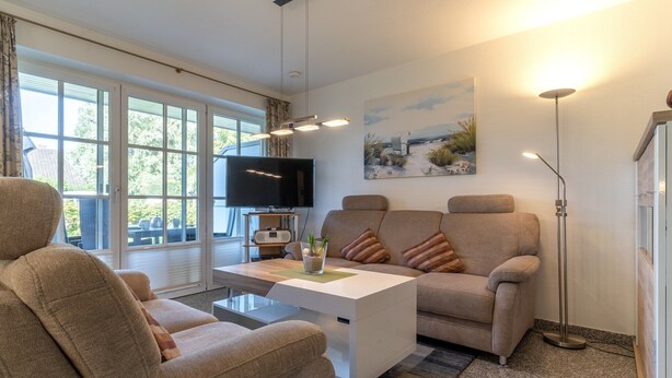 A modern living room with a sofa, a coffee table, a flat-screen TV, and a painting on the wall.