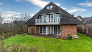 A two-story house with a balcony, brick exterior, and a well-maintained lawn.