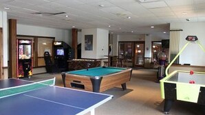 A pool table, ping pong table, and a foosball table in a room with a ceiling and walls. - # 127 Two Bedroom Condo with private entry (Lincoln)