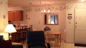 A dining area with a wooden table and chairs, a chandelier, and a mirror on the wall. - # 127 Two Bedroom Condo with private entry (Lincoln)