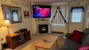 A living room with a fireplace, a television, a sofa, and a coffee table. - # 127 Two Bedroom Condo with private entry (Lincoln)
